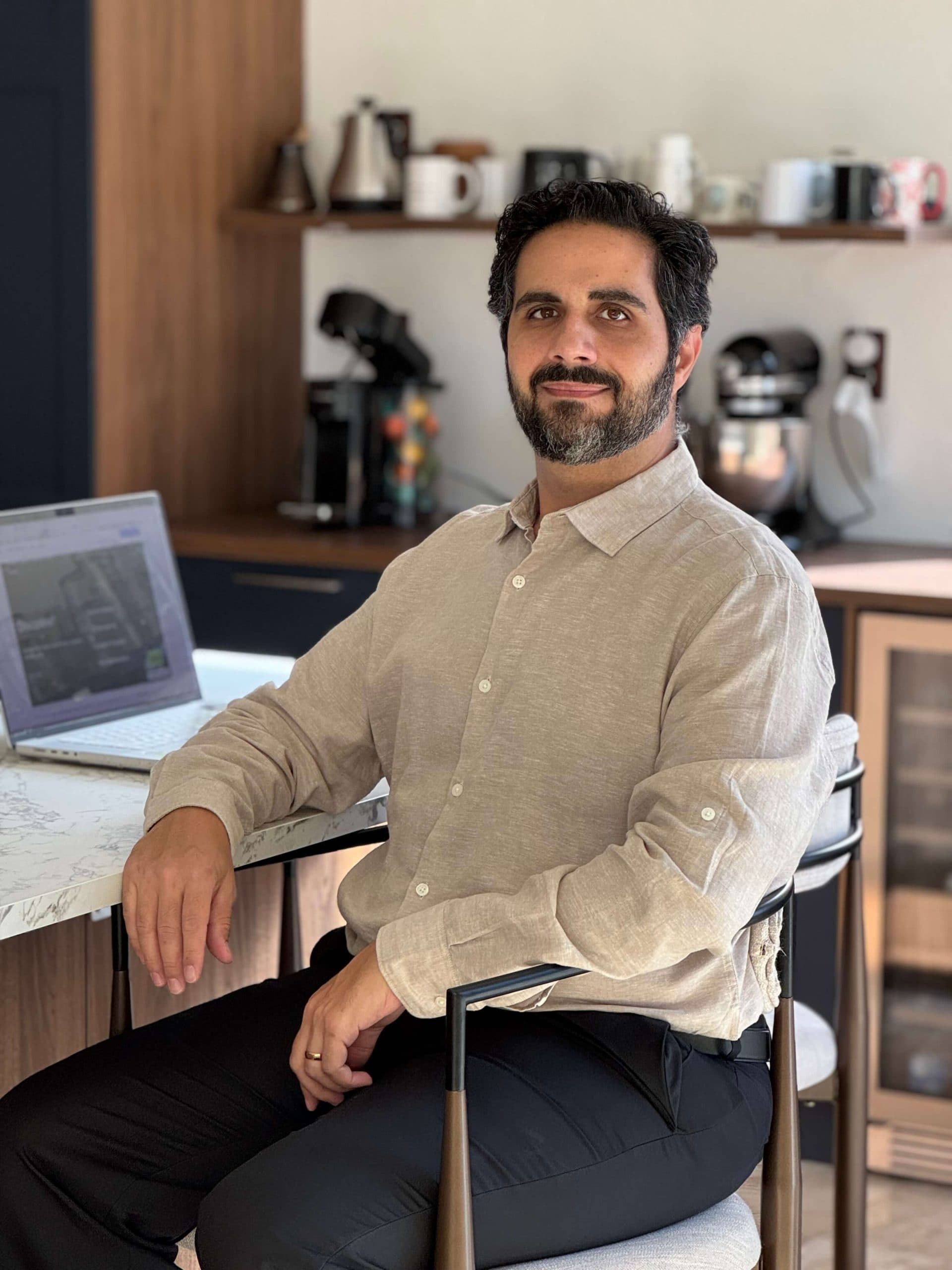 Mark Ohanesian sitting at counter with laptop smiling at camera